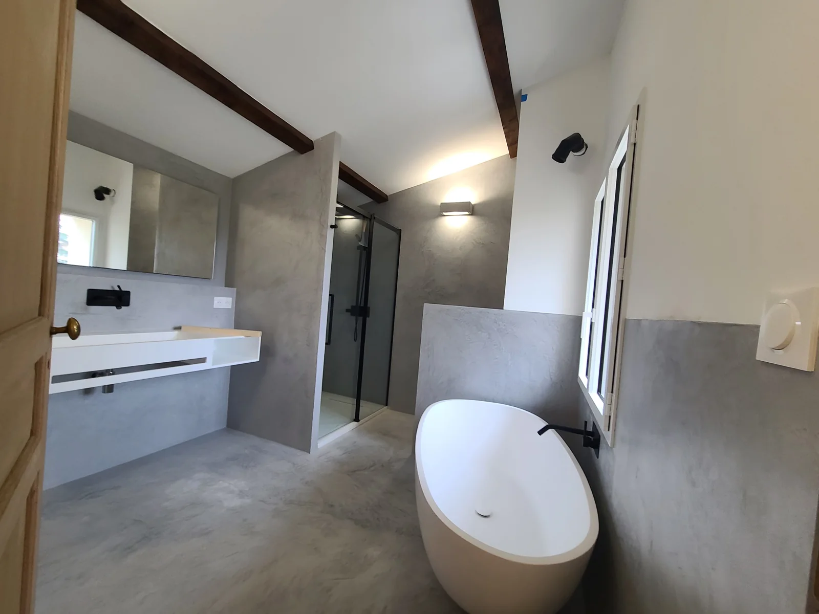 Salle de bain sous rampant, baignoire, vasque et poutres apparentes